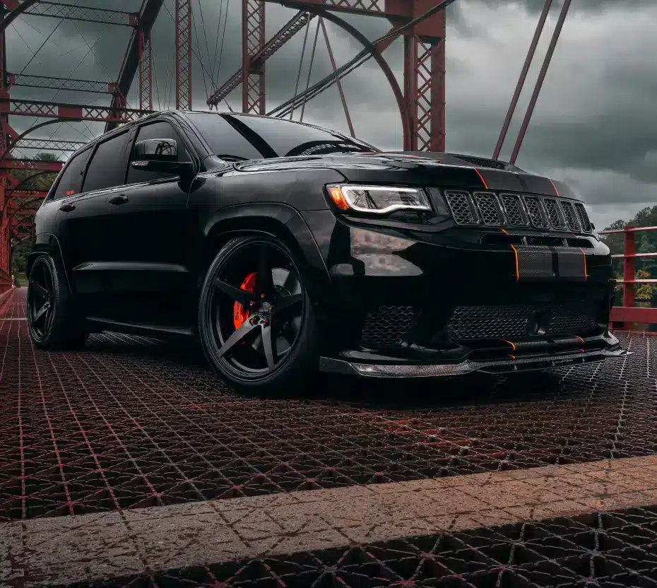 Black SUV on a bridge with a grey cloudy sky in the background.