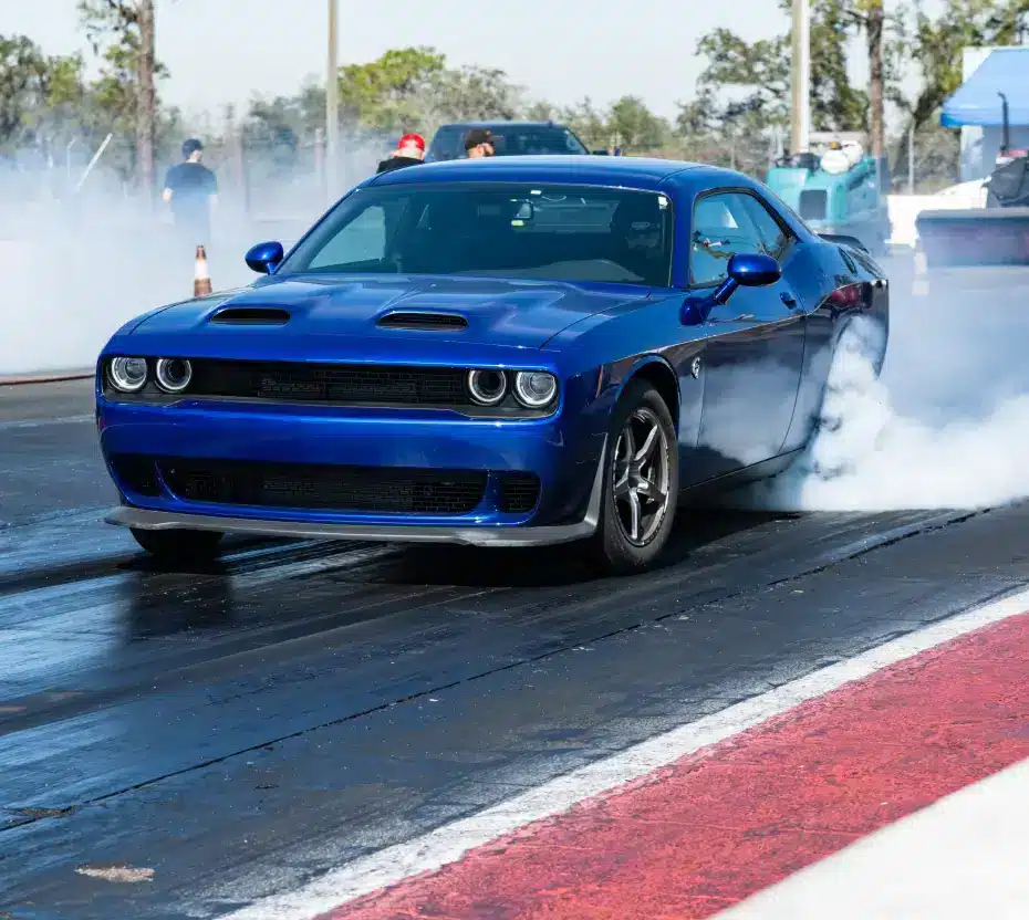 Blue dodge drag racing with smoke billowing from the rear tires.